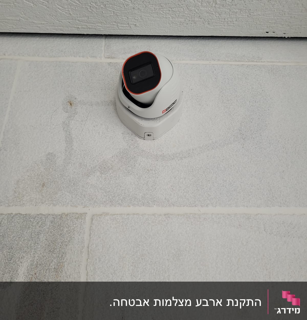 מצלמת אבטחה לבנה מותקנת על קיר לבן